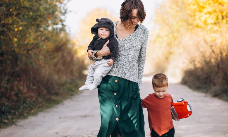 Mãe caminhando com dois filhos no parque