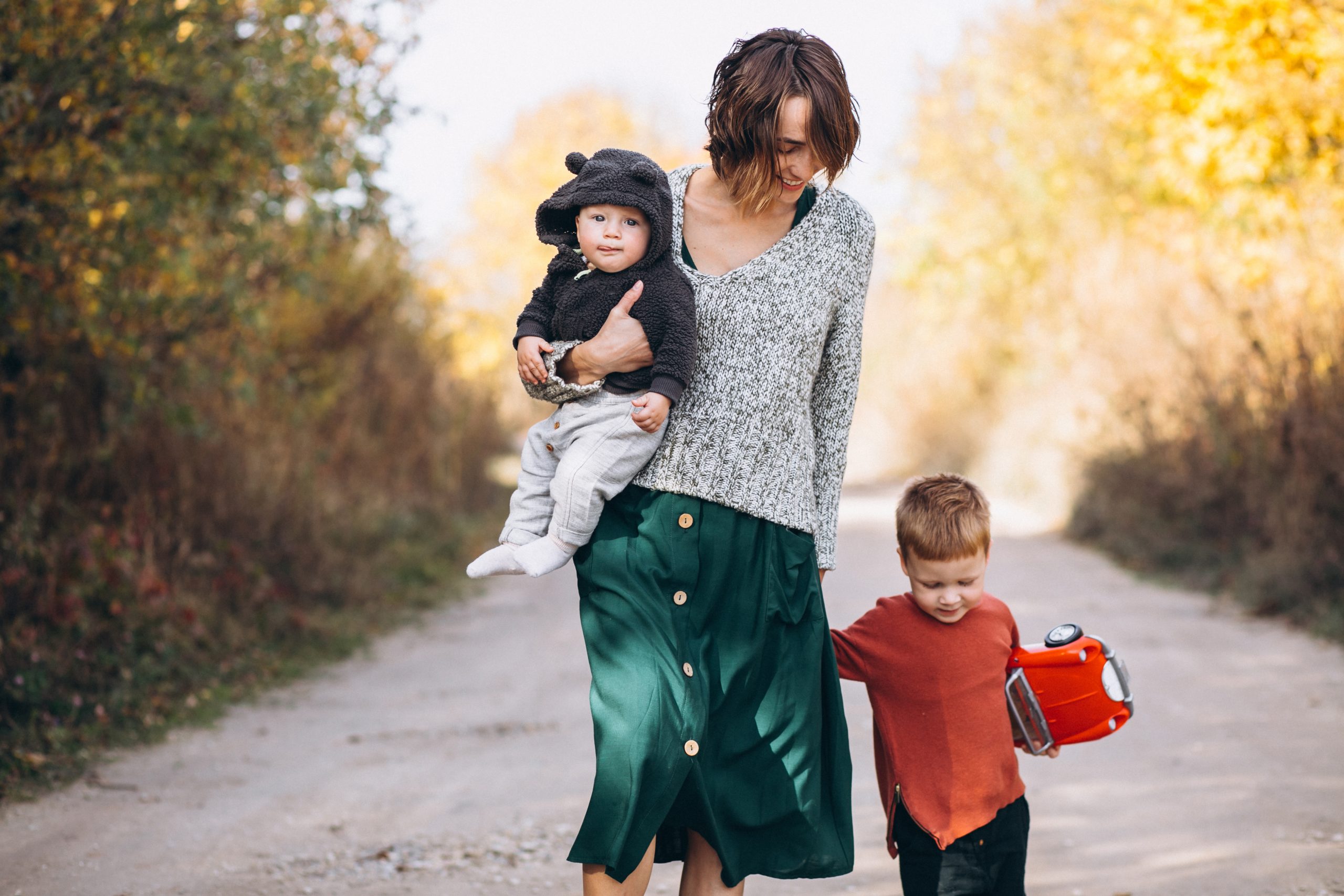 Mãe caminhando com dois filhos no parque